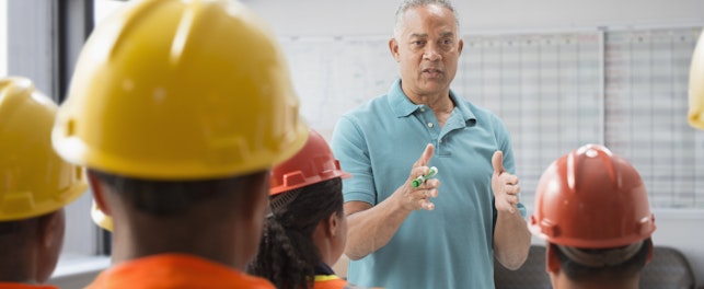 Formateur en train de donner une présentation à des ouvriers portant des casques de sécurité.