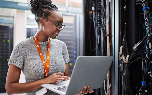 Woman Using a Laptop in a Server Room