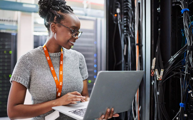 Woman Using a Laptop in a Server Room