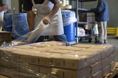 Worker Wrapping Packages with Plastic Wrap