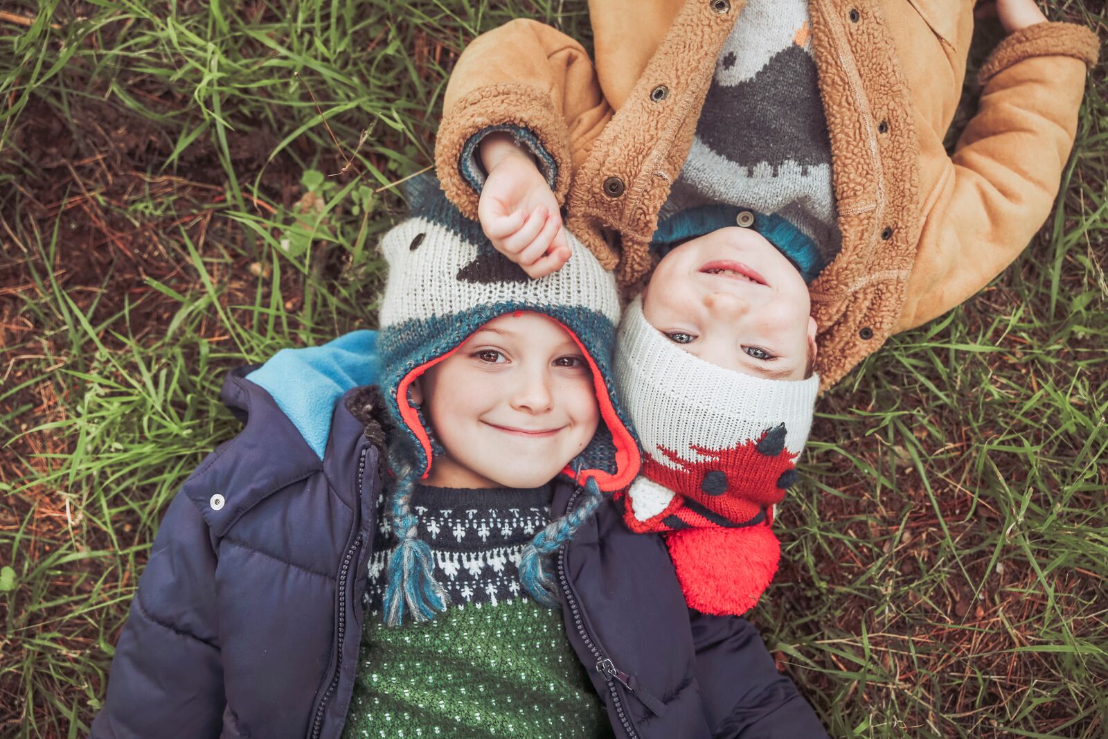 Boys Wearing Winter Clothes Laying down in the Grass