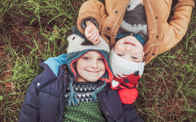 Boys Wearing Winter Clothes Laying down in the Grass