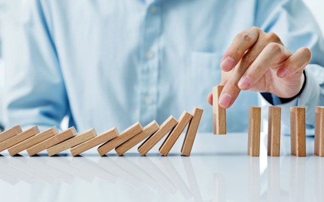 Businessman Hand Picking up One Domino