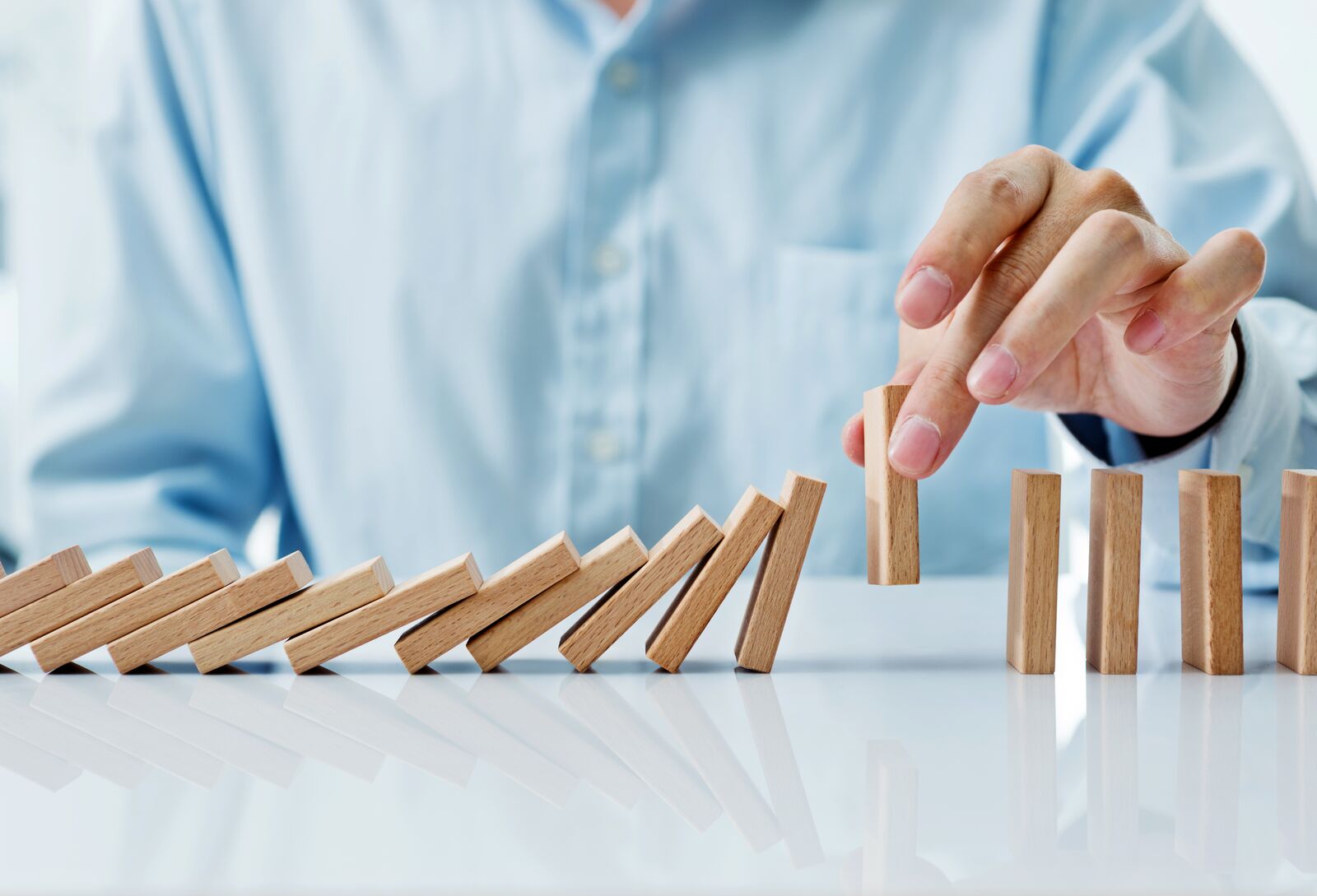 Businessman Hand Picking up One Domino