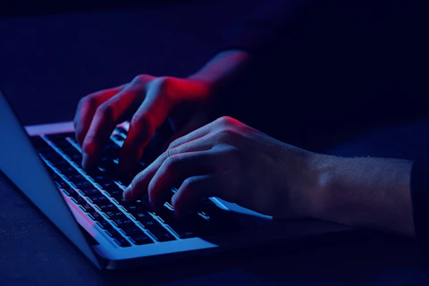 Cyber Security Concept Professional hacker with laptop sitting at table, closeup
