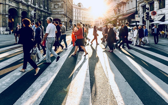 Mensen die de straat oversteken met licht van de zon