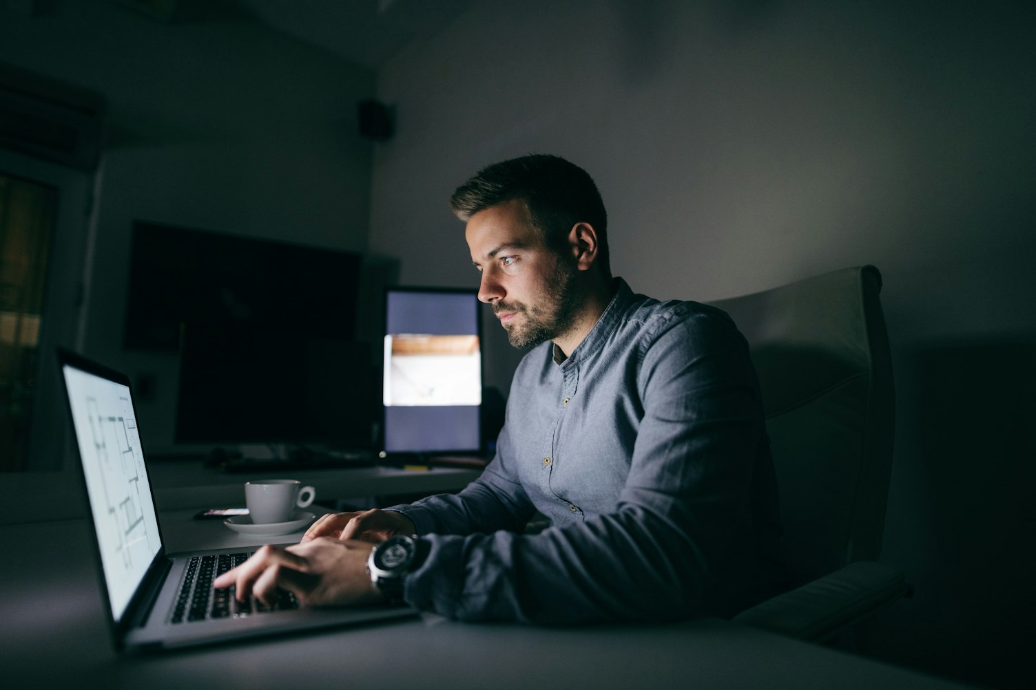 Young Caucasian Worker Typing in Laptop while Sitting in Office Late Night