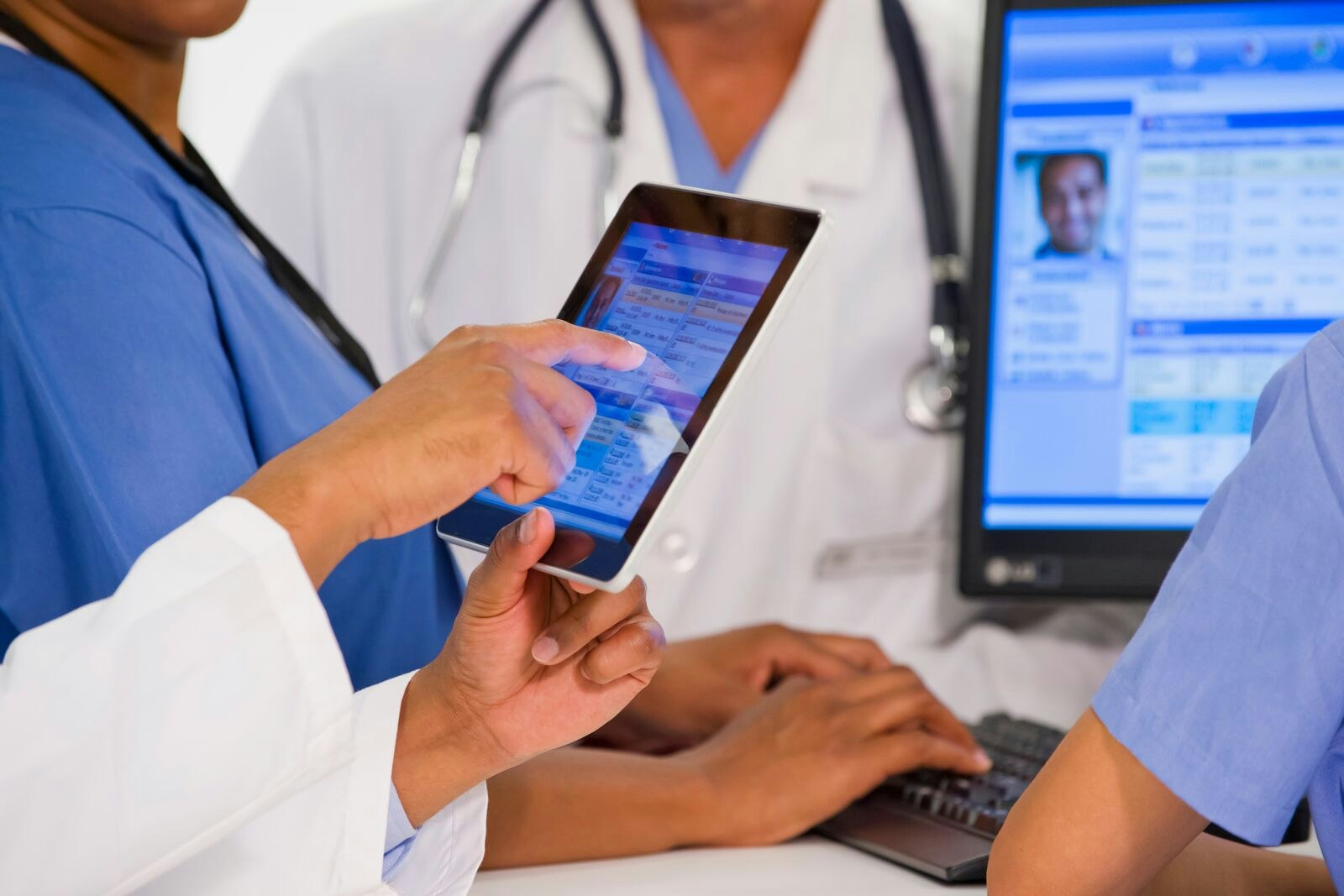 Doctors consulting patient file on mobile tablet