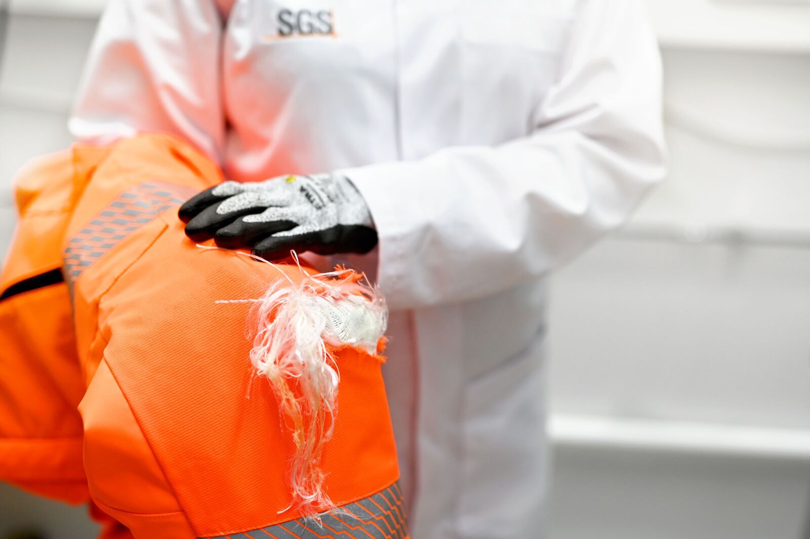 Testing engineer demonstrates safety trousers after testing with a chainsaw