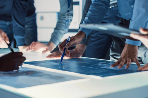 Ingénieurs, scientifiques et développeurs réunis autour d'une table de conférence éclairée au Centre de recherche technologique, Talking, Trouver des solutions et Analyser la conception de moteurs industriels. Gros plan sur les mains
