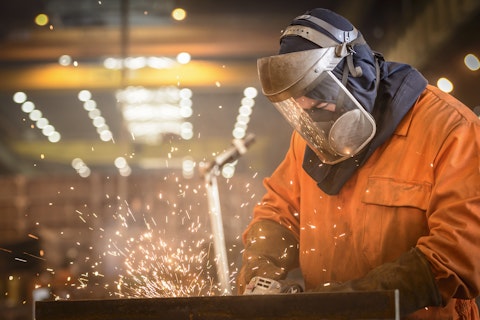Worker Grinding Metal in Factory