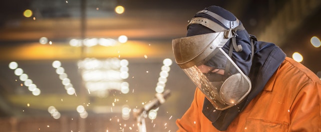 Worker Grinding Metal in Factory
