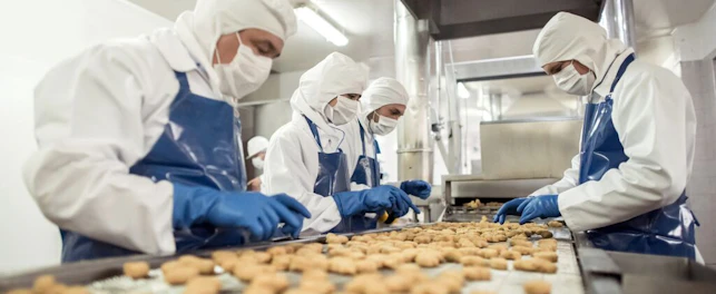 workers at food factory doing quality control on production line