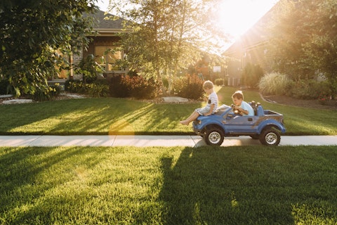 siblings playing with toy car on sidewalk at yard