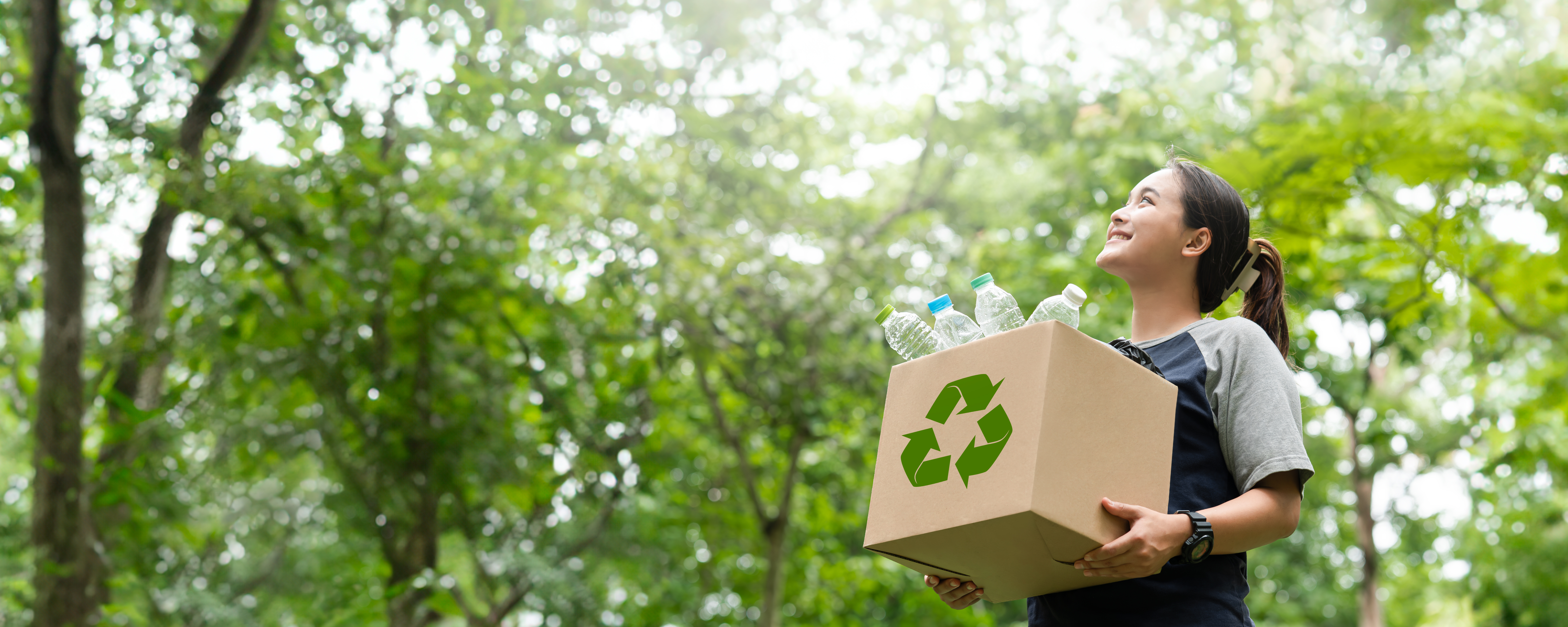 woman holding a garbage box recycling concept Recycle, recycle, plastic-free, junk food plastic packaging. on a forest nature green background copy space plastic recycling Environmental pollution, ecology concept.
