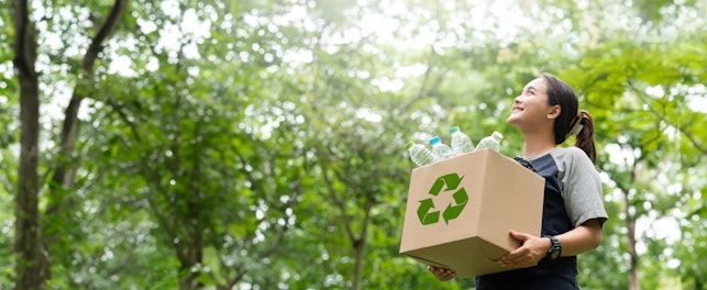 woman holding a garbage box recycling concept Recycle, recycle, plastic-free, junk food plastic packaging. on a forest nature green background copy space plastic recycling Environmental pollution, ecology concept.