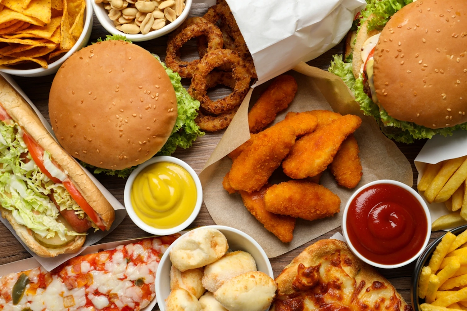 Patatas fritas, hamburguesas y otra comida rápida como fondo, top view