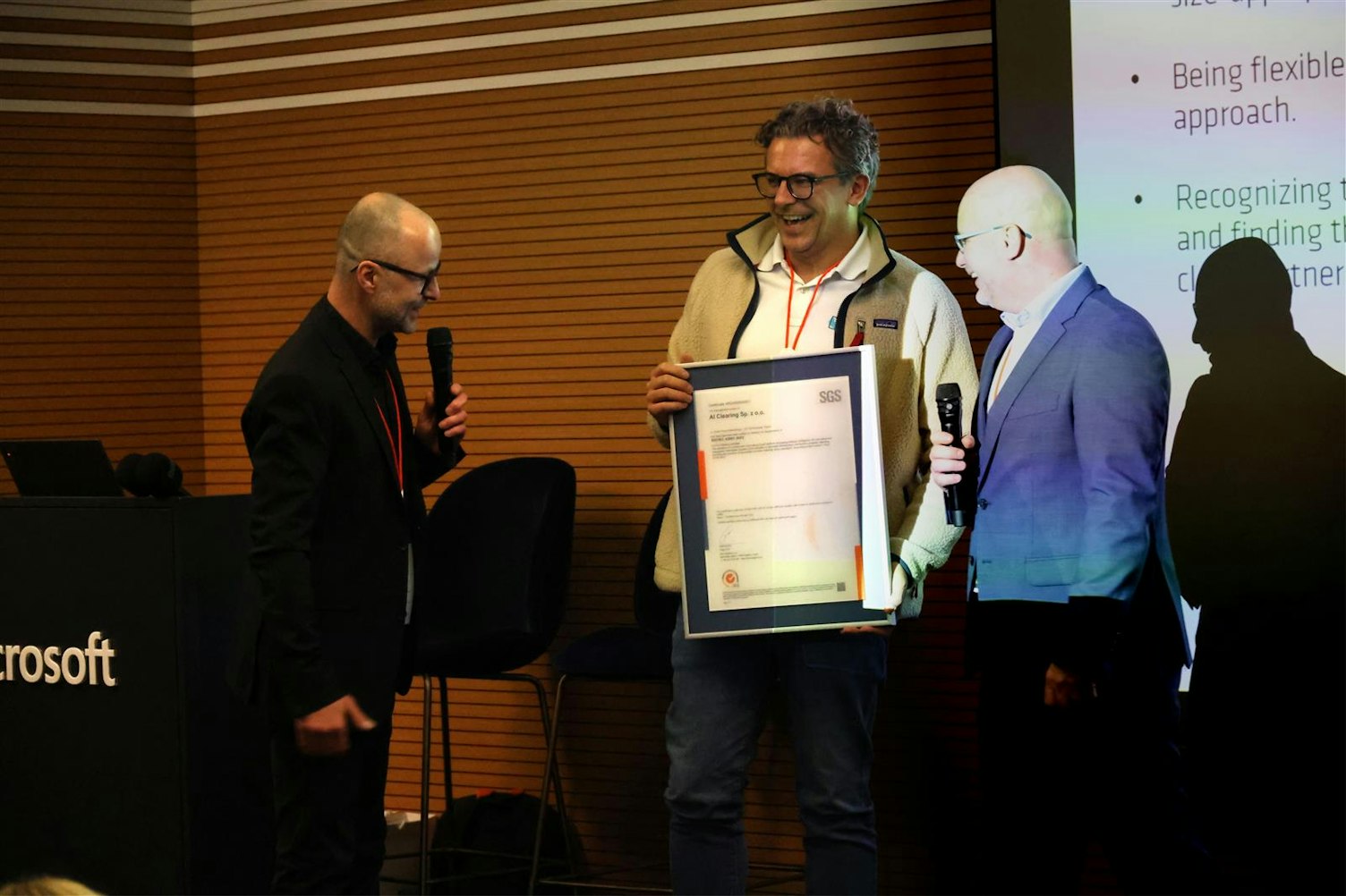 Adam Wiśniewski i Dariusz Cieśla odbierają z rąk Michała Cichockiego ozdobny certyfikat ISO/IEC 42001 dla AiClearing