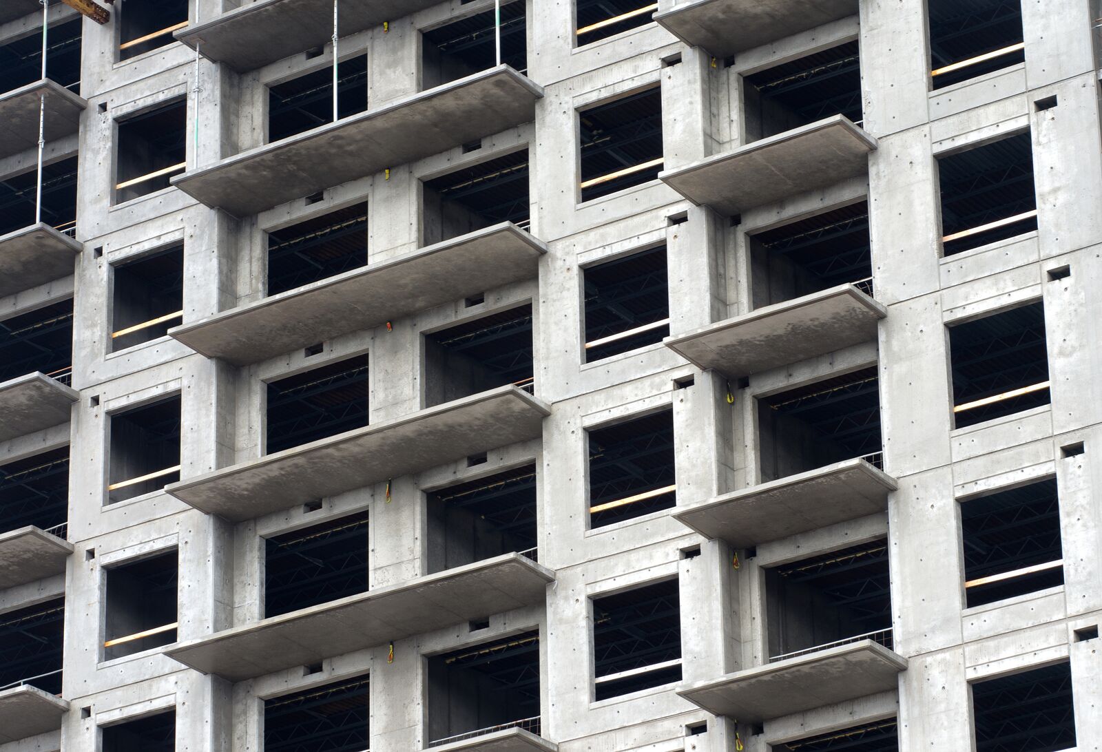 Na zdjęciu widoczny jest budynek w stanie surowym, z wieloma oknami, w trakcie budowy.