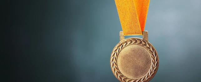 Złoty medal na pomarańczowej wstążce.