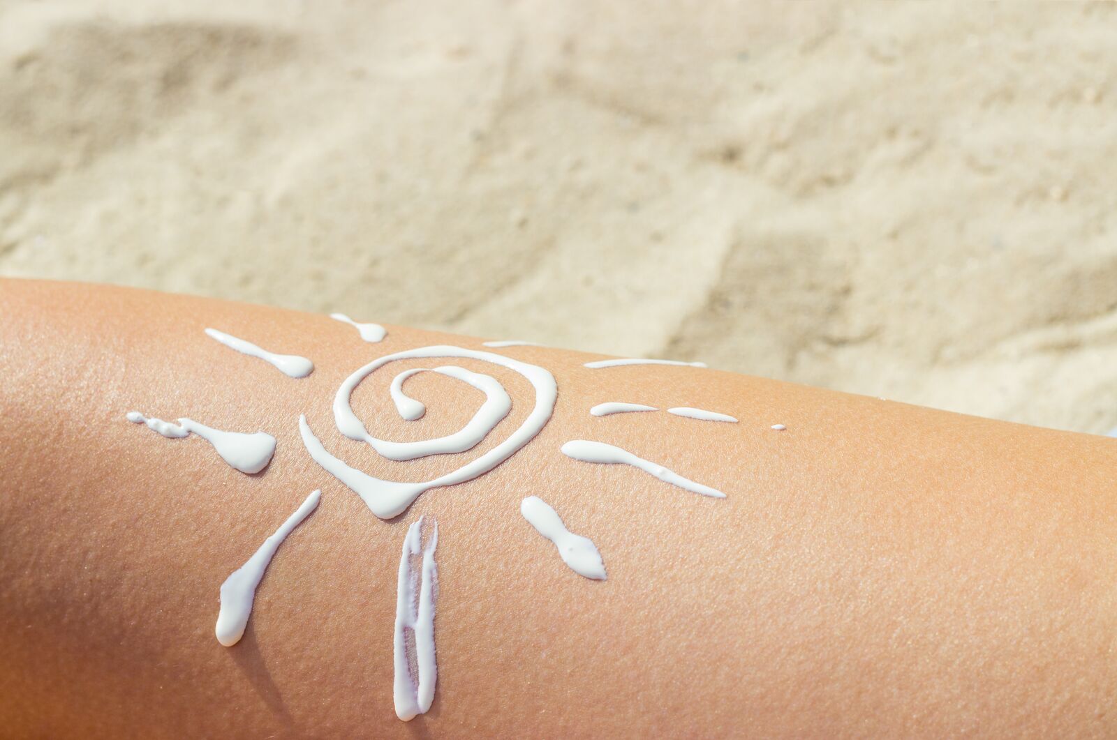 Kosmetyk przeciwsłoneczny ułożony w kształt słońca na skórze.