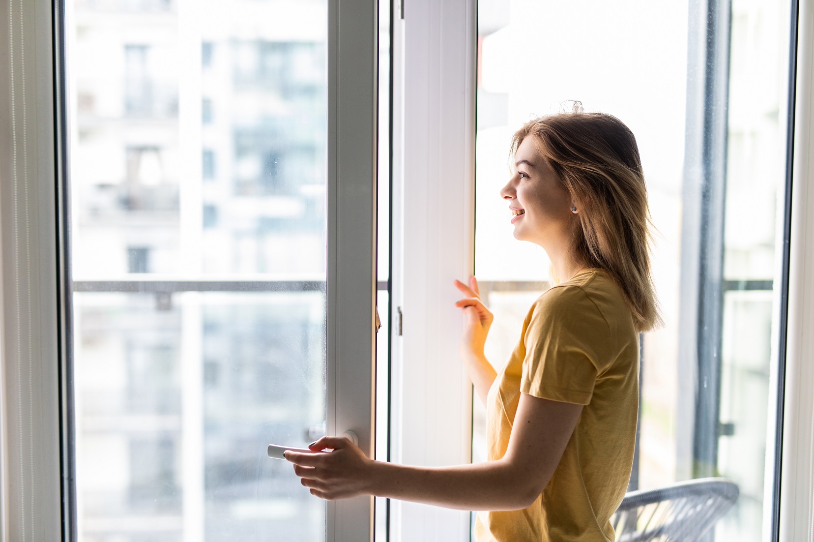 Kobieta otwierająca okno w mieszkaniu.