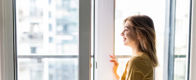 Kobieta otwierająca okno w mieszkaniu.