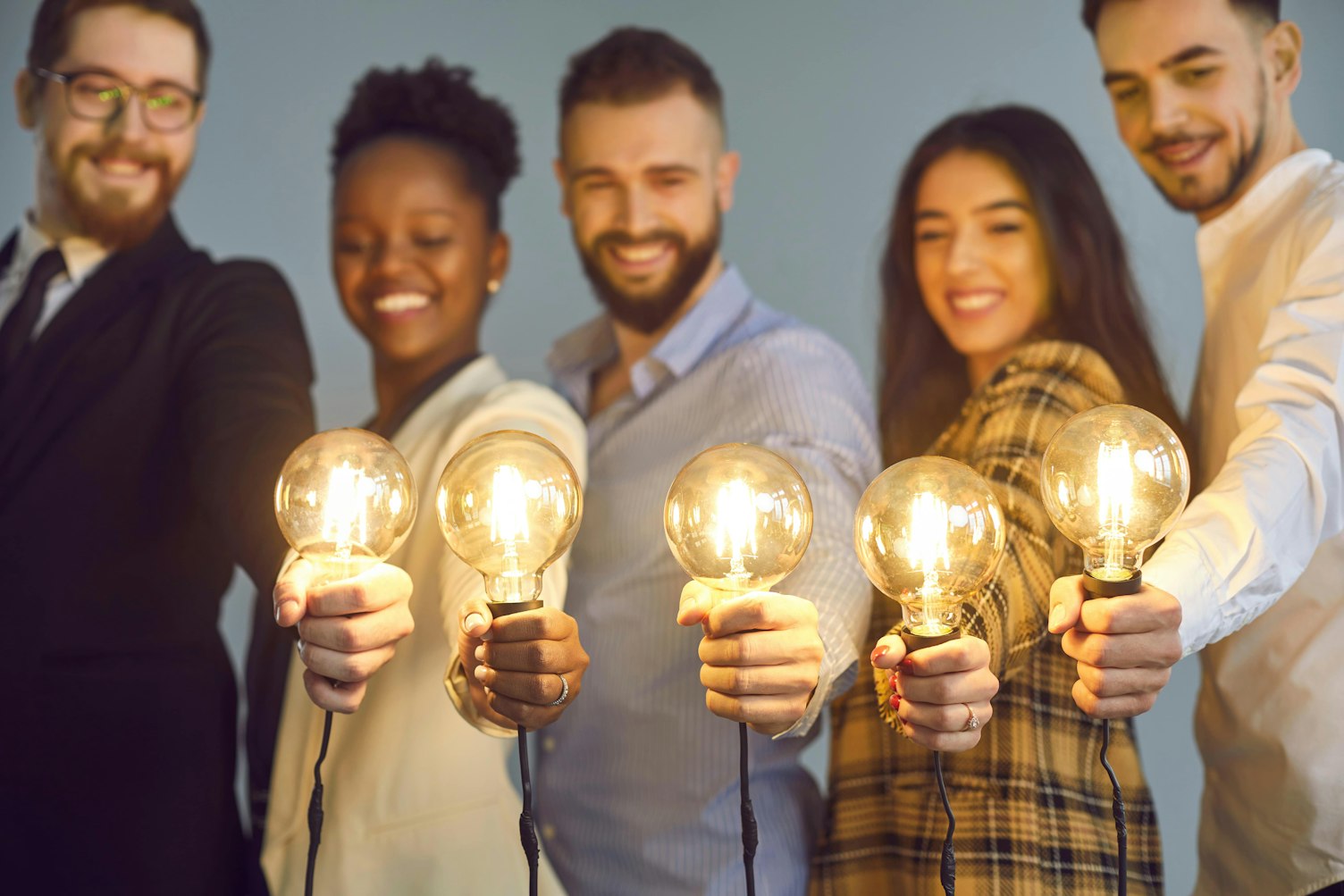 Business Colleagues Holding Shining Light Bulbs