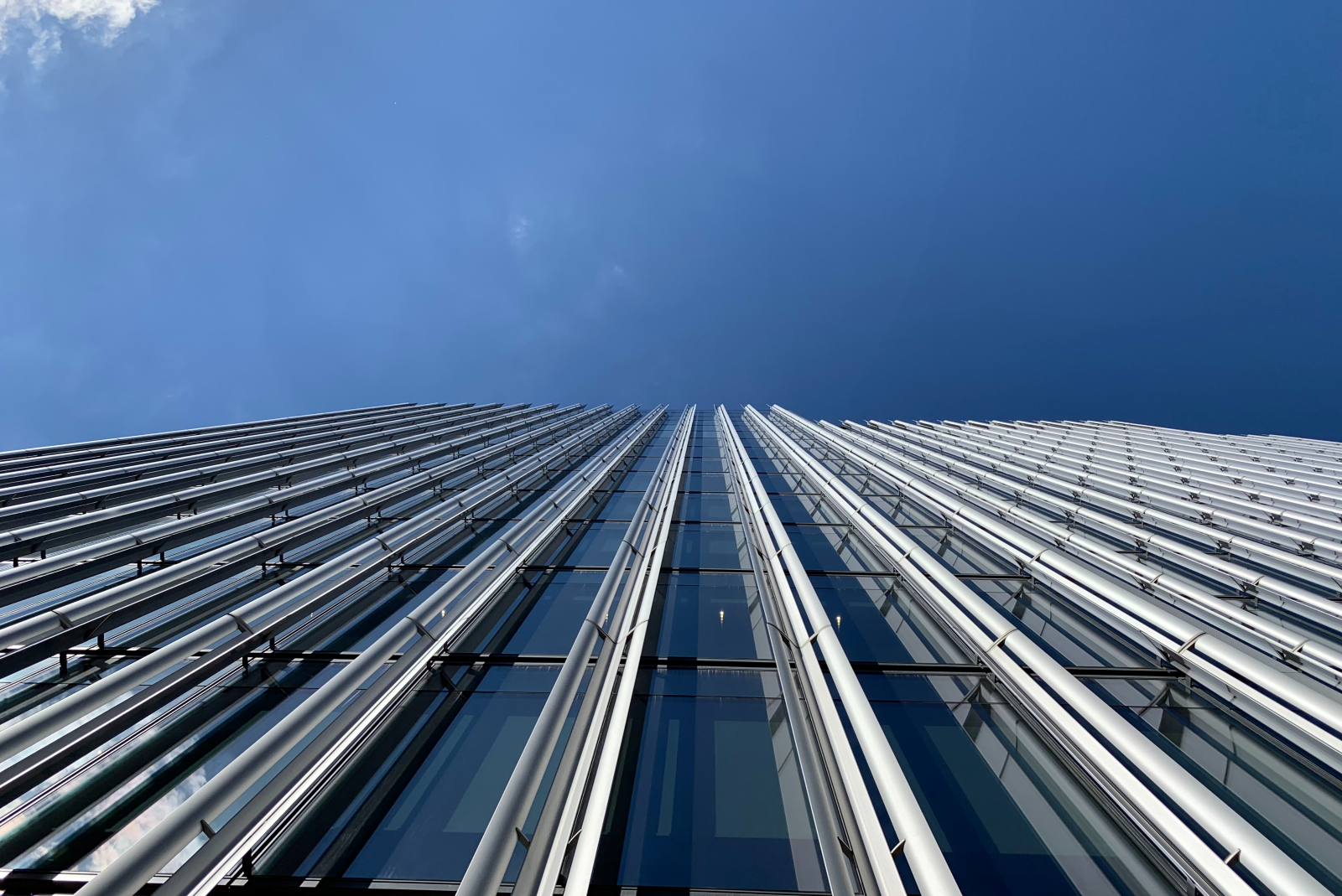 Fotografowany od dołu wysoki, solidny budynek, z widocznym nad nim niebieskim niebem.