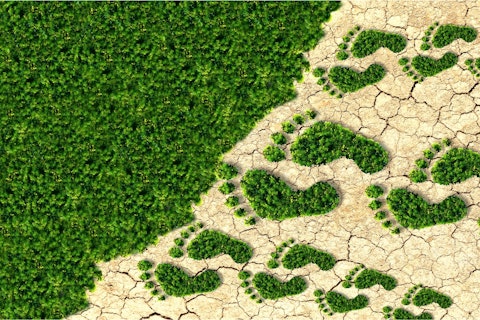 Zielone ślady stóp zmierzające po suchej ziemi do zieleni