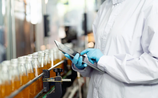 Inspector Checking Bottles on a Conveyor Belt in Beverage Factory