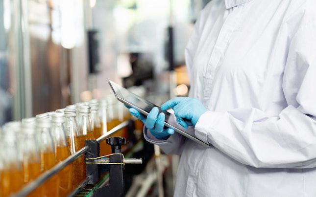 Inspector Checking Bottles on a Conveyor Belt in Beverage Factory