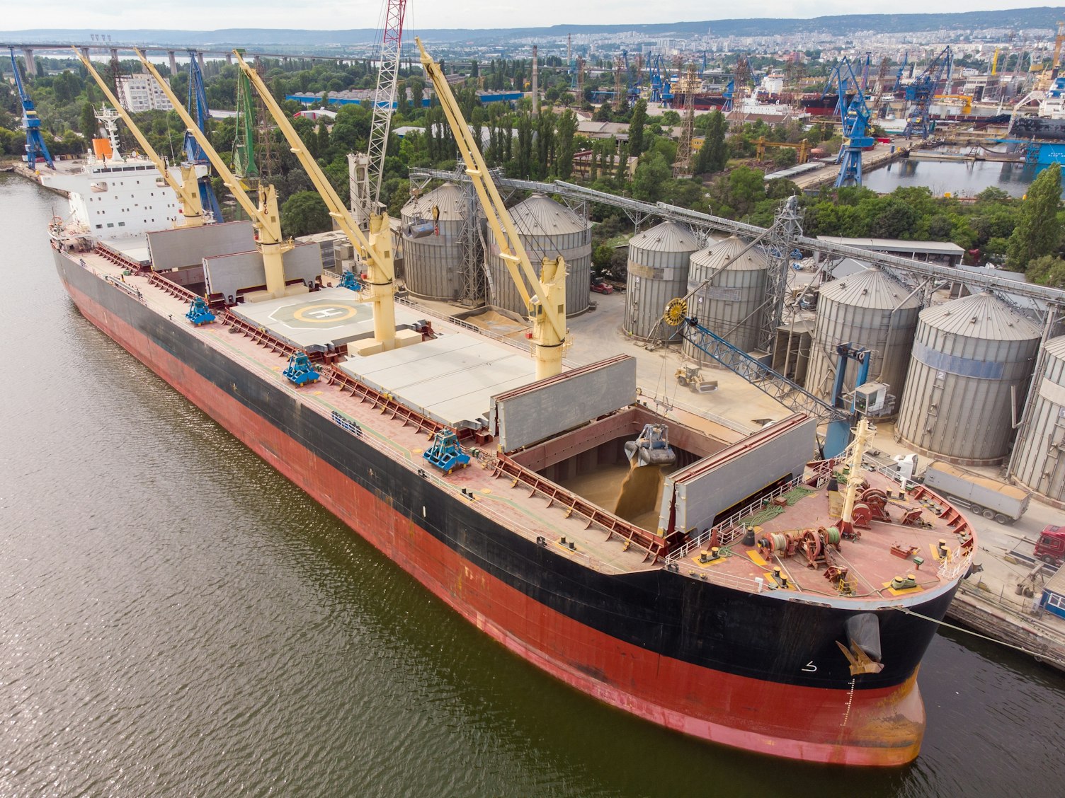 Loading grain into holds of sea cargo vessel in seaport from silos of grain storage
