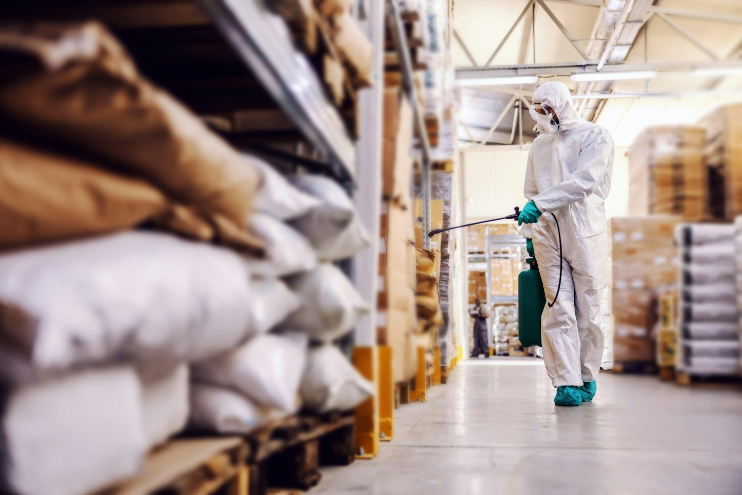 Man in Protective Suit Disinfecting Warehouse