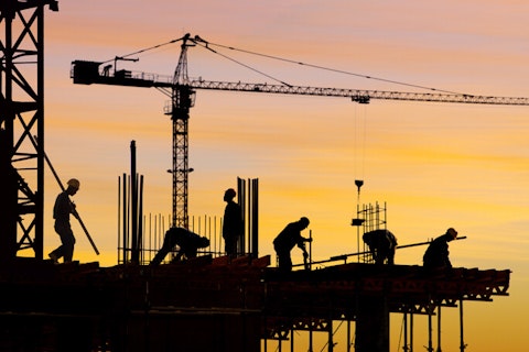 Construction workers silhouette against orange sky