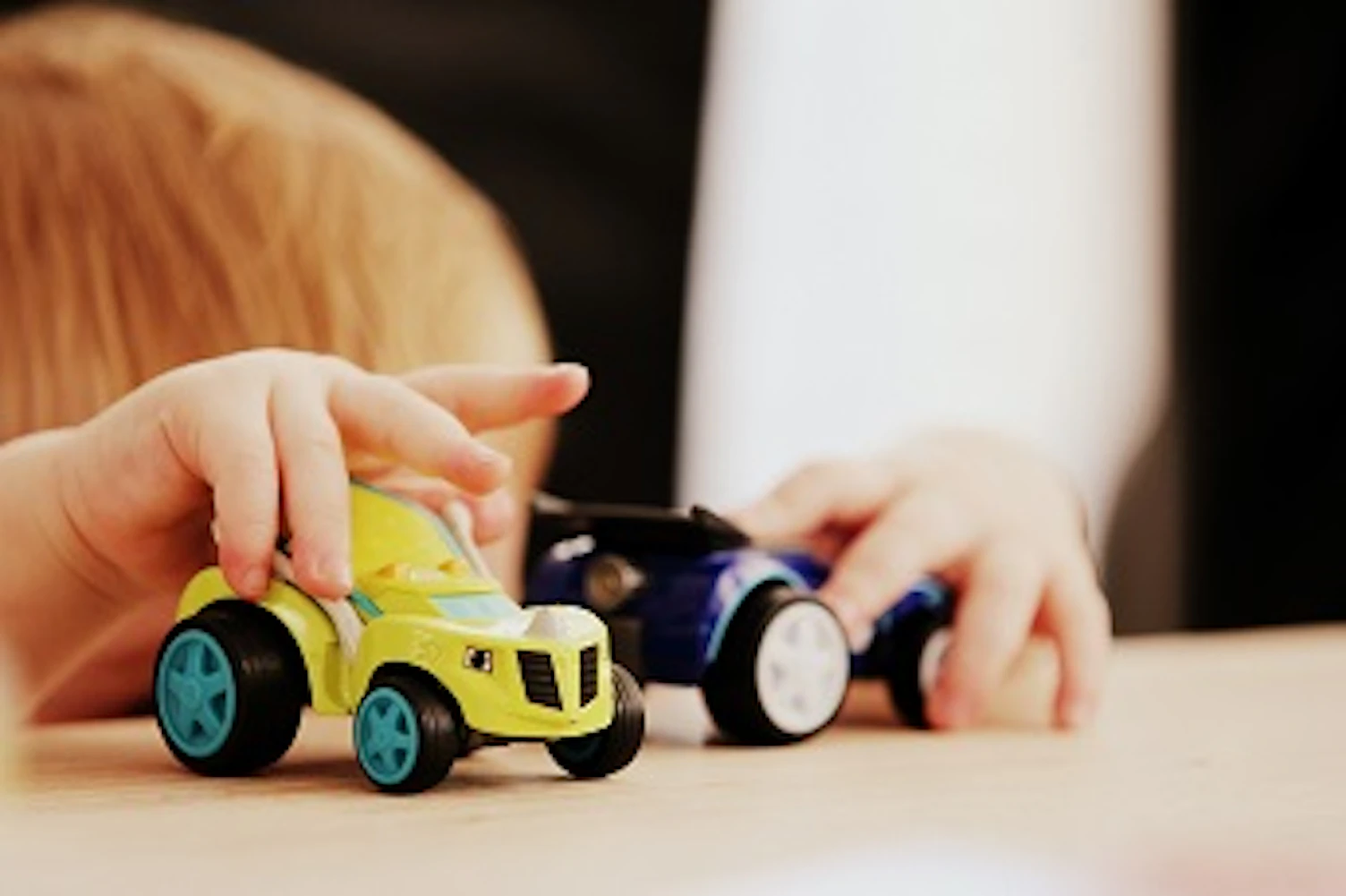 child playing with two assortedcolor car plastic toysunsplash