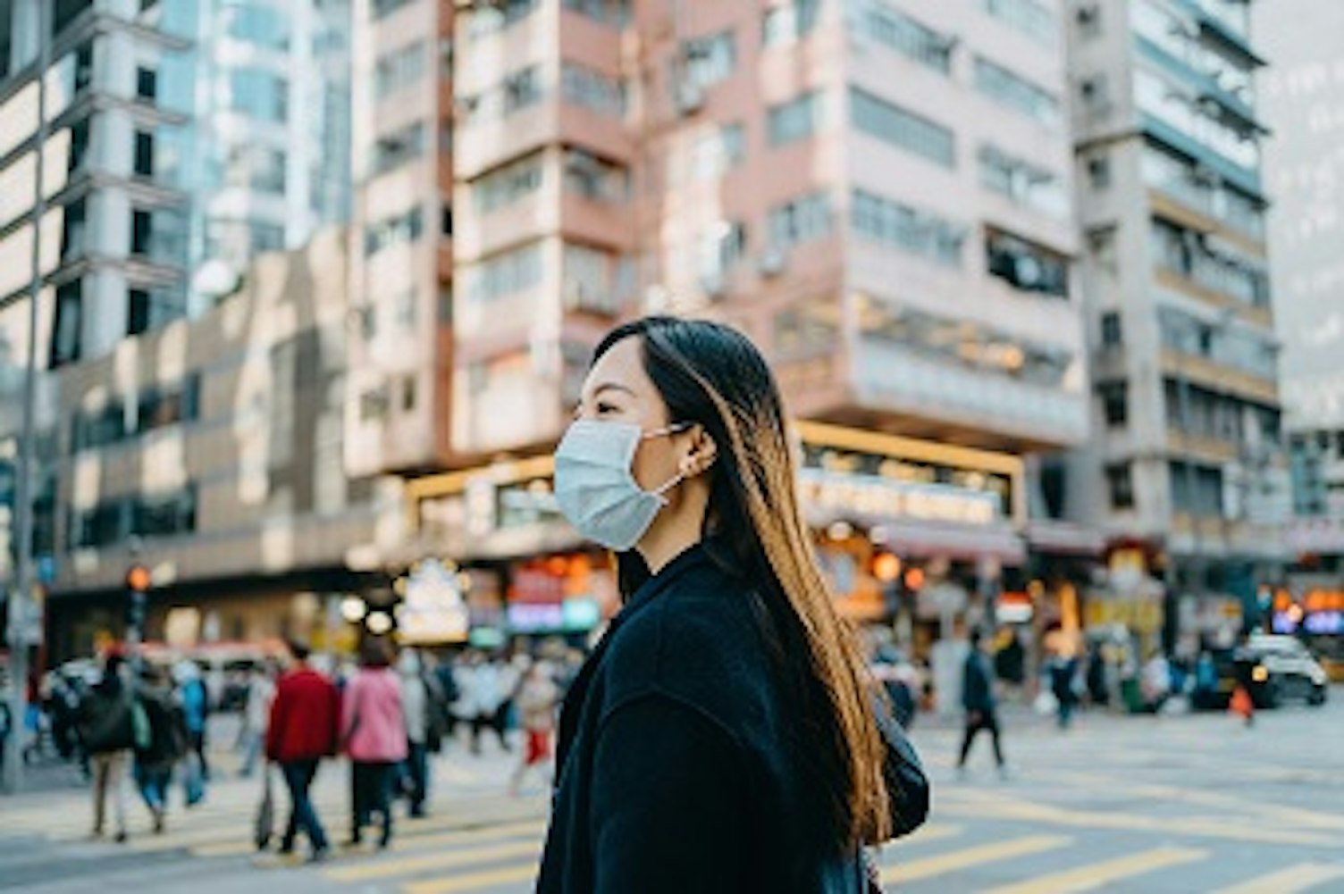 orig businesswoman wearing protective face mask walking down the street 344px