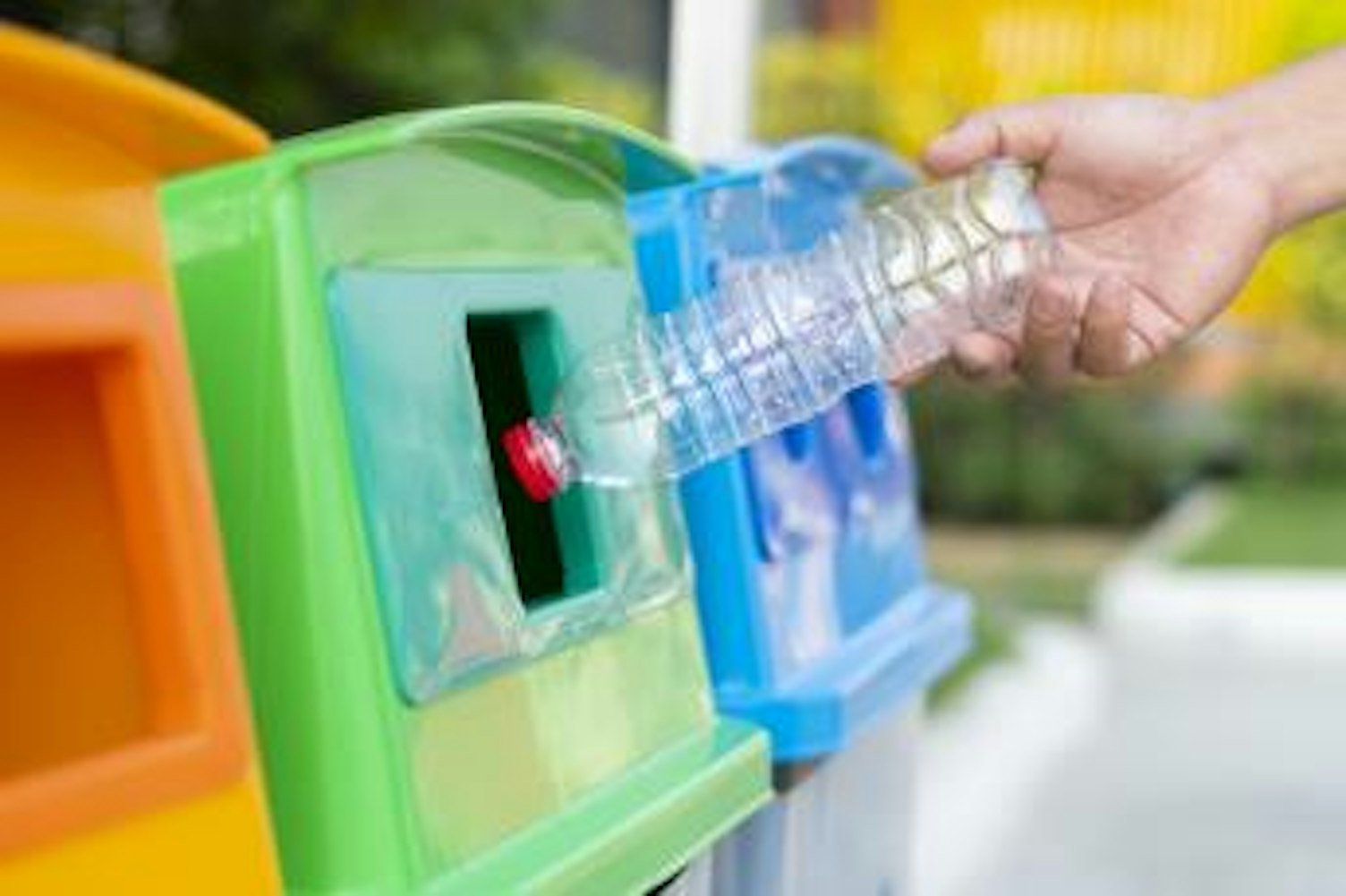 orig close up hand throwing empty plastic bottle into the trash recycling Getty