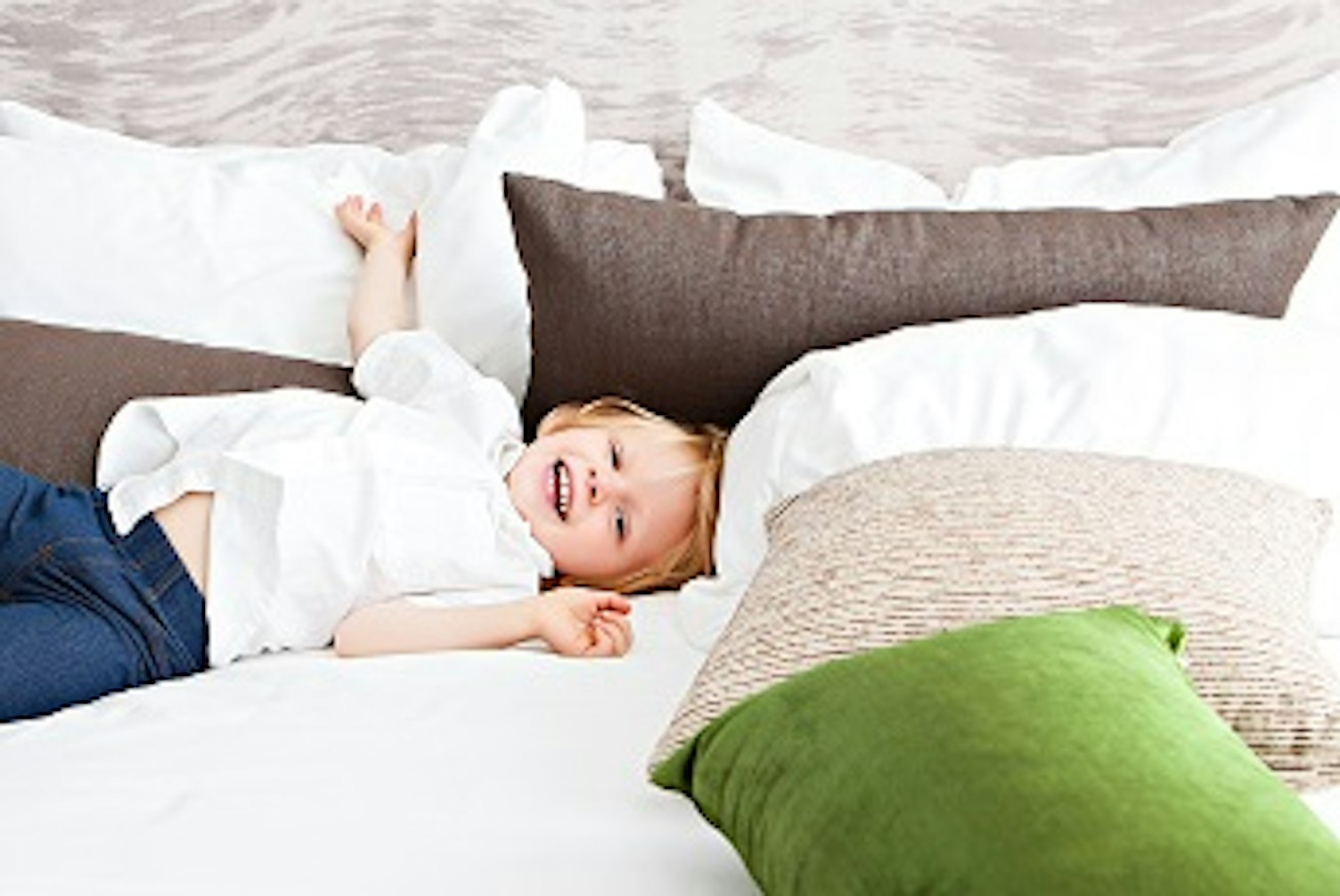 orig happy kid amongst cushions on a bed unsplash