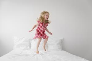 orig little girl jumping on bed with white duvet Getty740526949