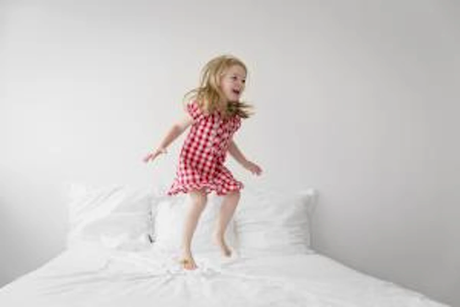 orig little girl jumping on bed with white duvet Getty740526949