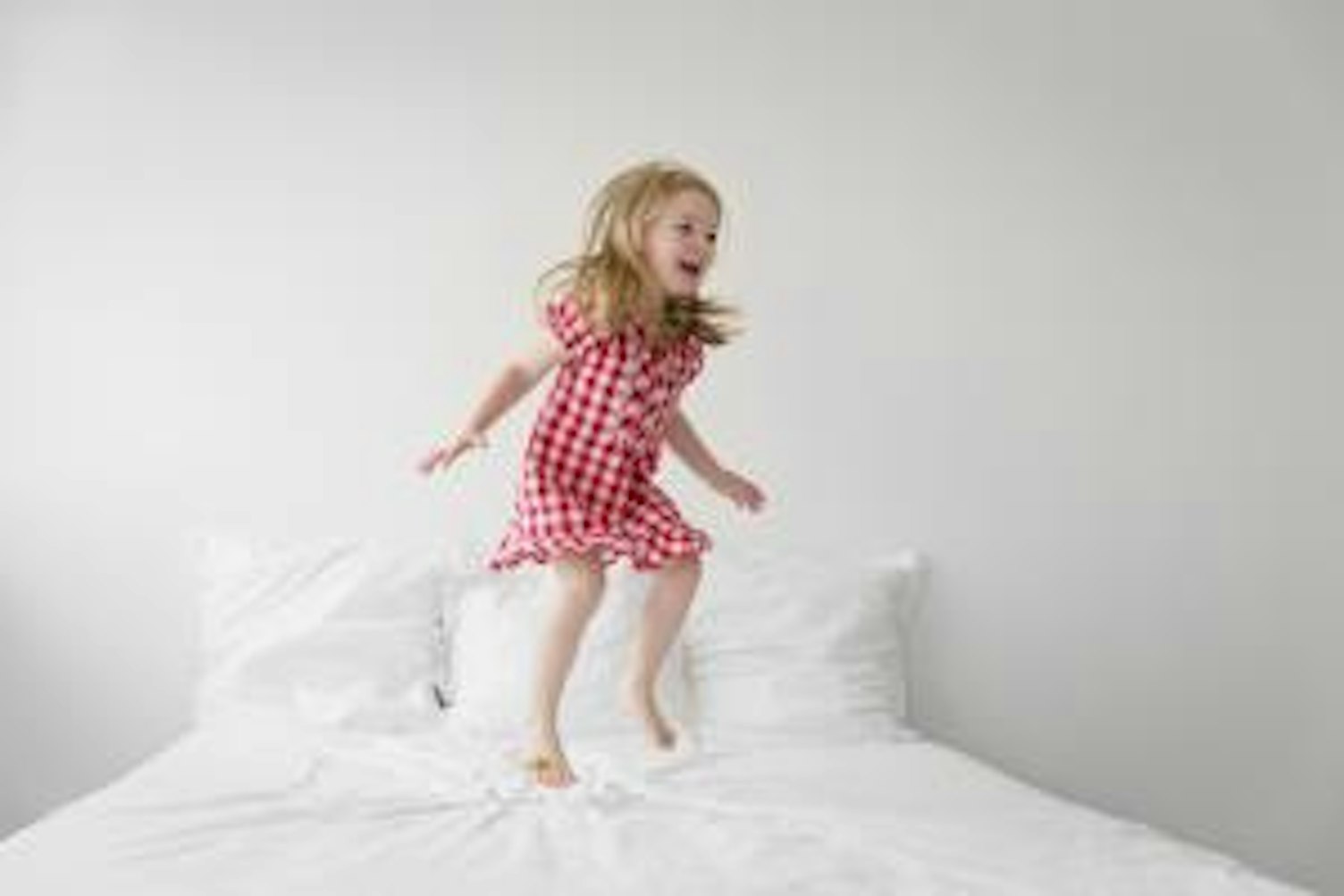 orig little girl jumping on bed with white duvet Getty740526949