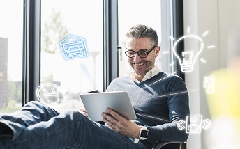 orig man sitting in office using digital tablet to remotecontrol his smart home