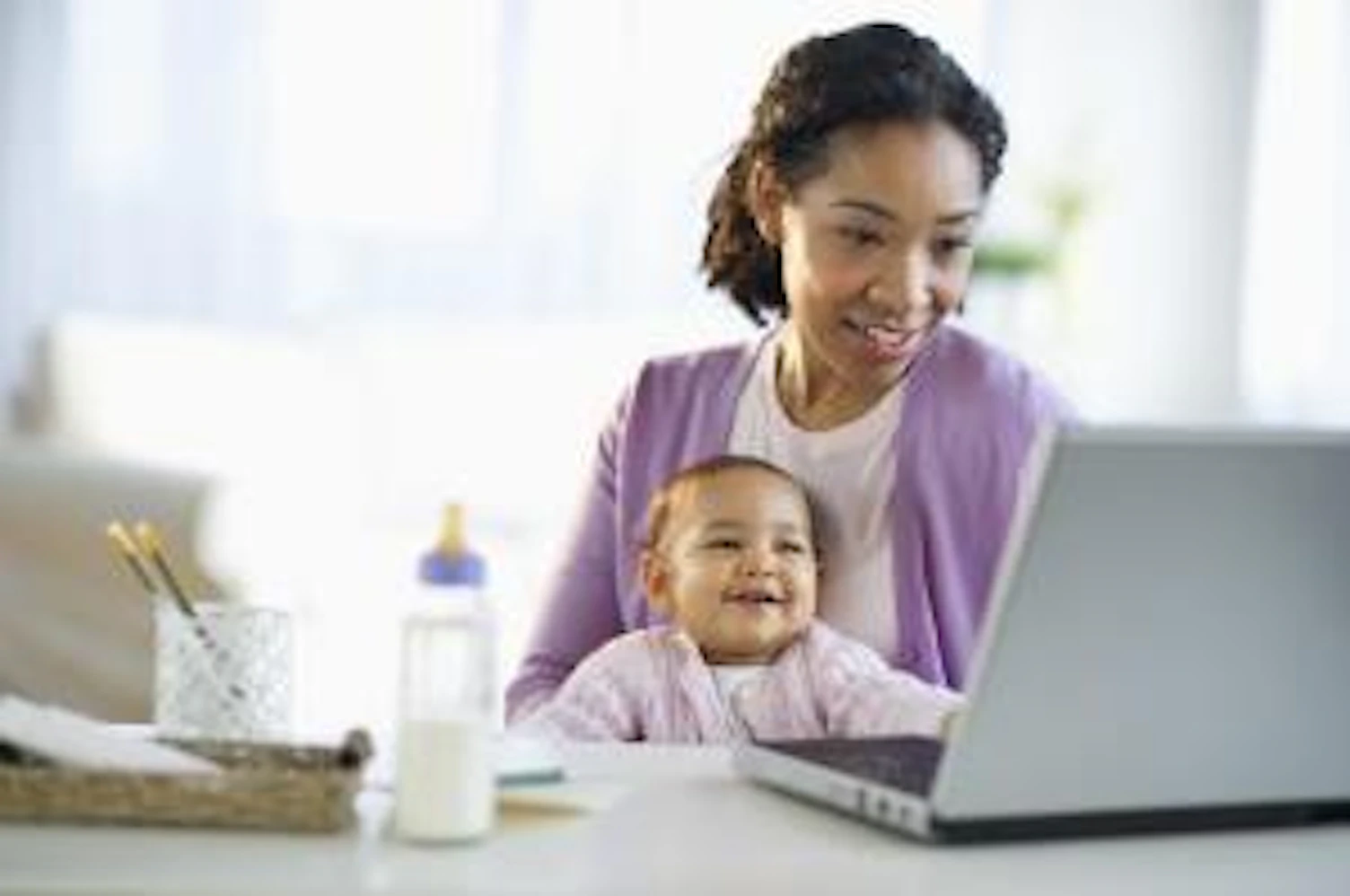 orig mixed race woman holding baby and using laptop Getty112704664
