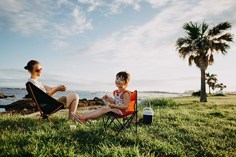 orig mother and daughter enjoying camping sitting in folding chairs