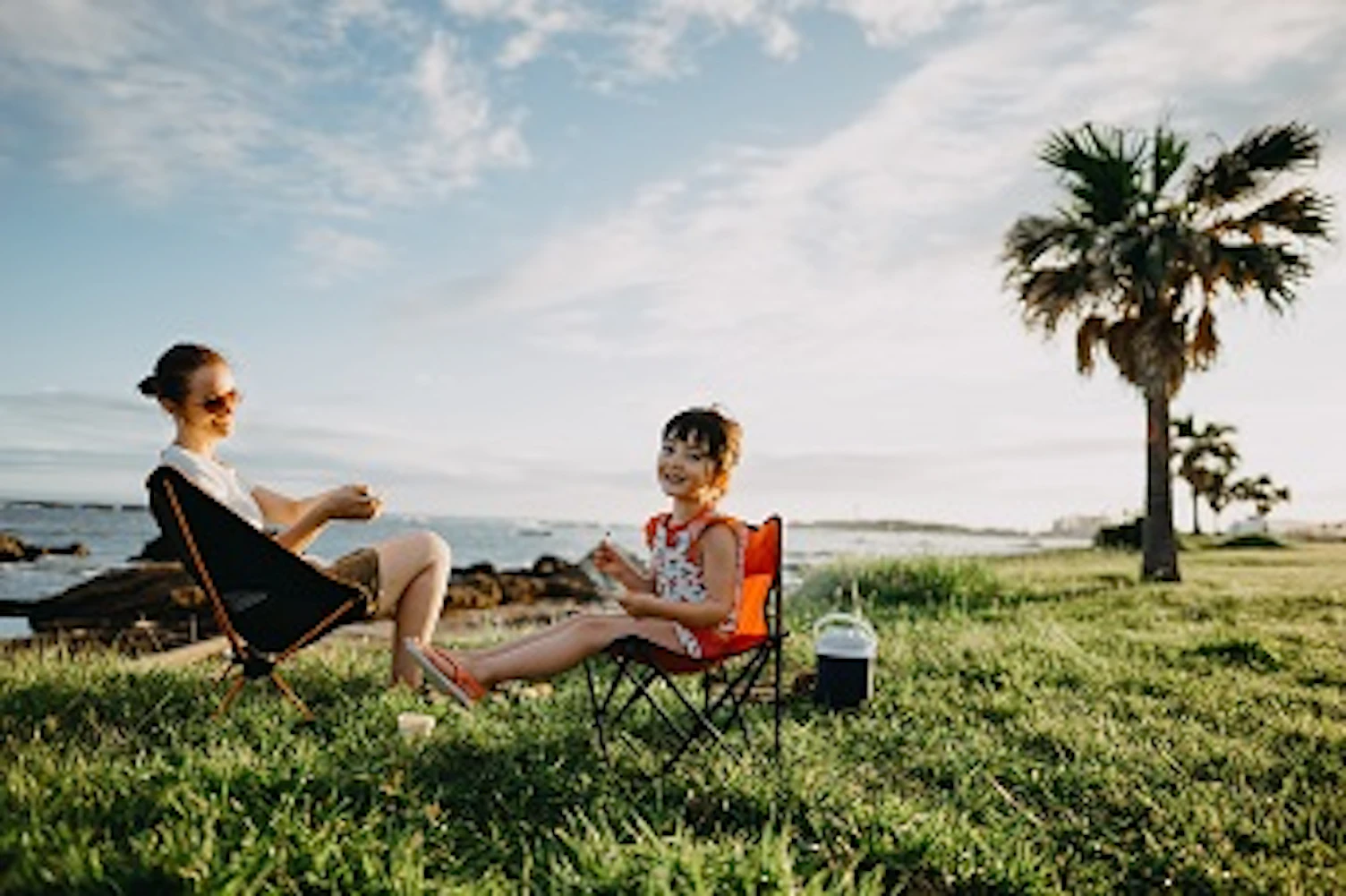 orig mother and daughter enjoying camping sitting in folding chairs