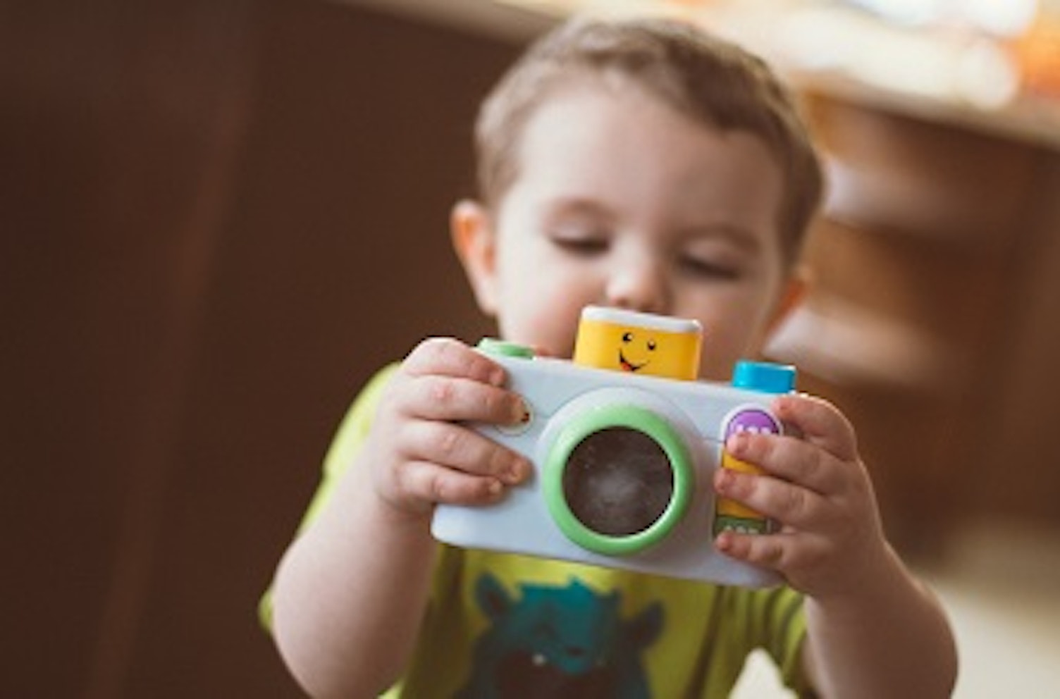 orig toddler holding white camera toyunsplash