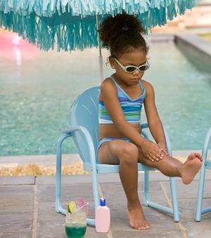 orig young girl sitting by pool putting on sun screen Getty82252774