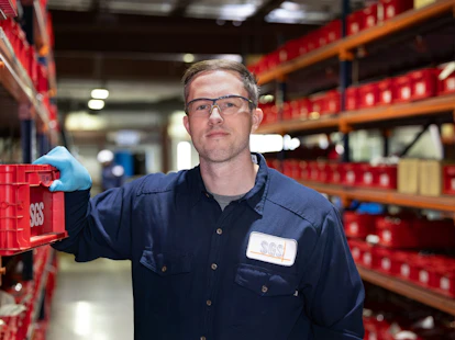 Worker in a warehouse holding a red crate