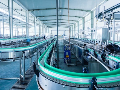 Usine de production de boissons avec chaîne de fabrication automatisée Chaîne de production automatisée dans une usine de fabrication de boissons, avec des convoyeurs et des équipements industriels modernes.